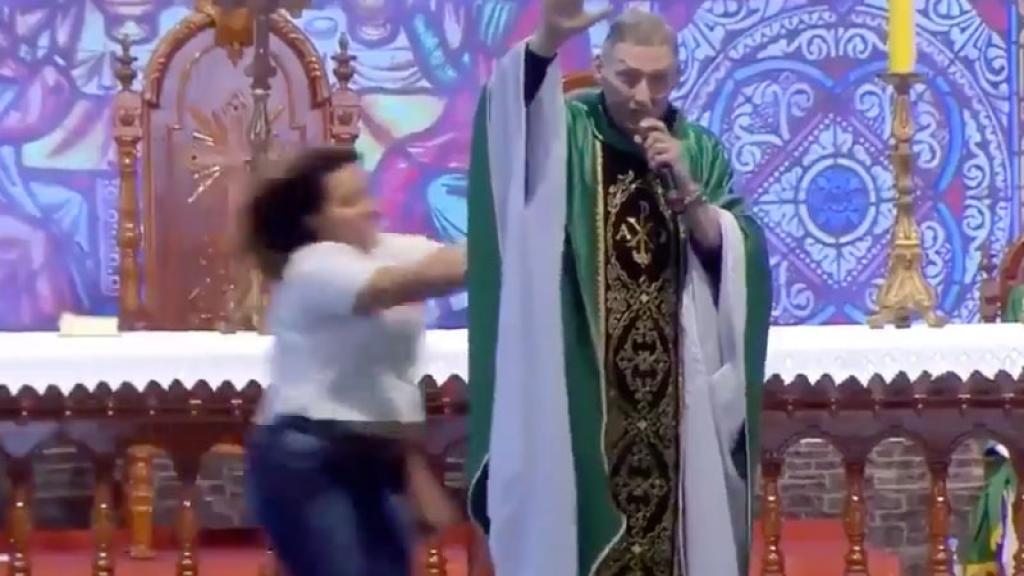 Mujer empuja y tira del escenario a sacerdote en plena misa.